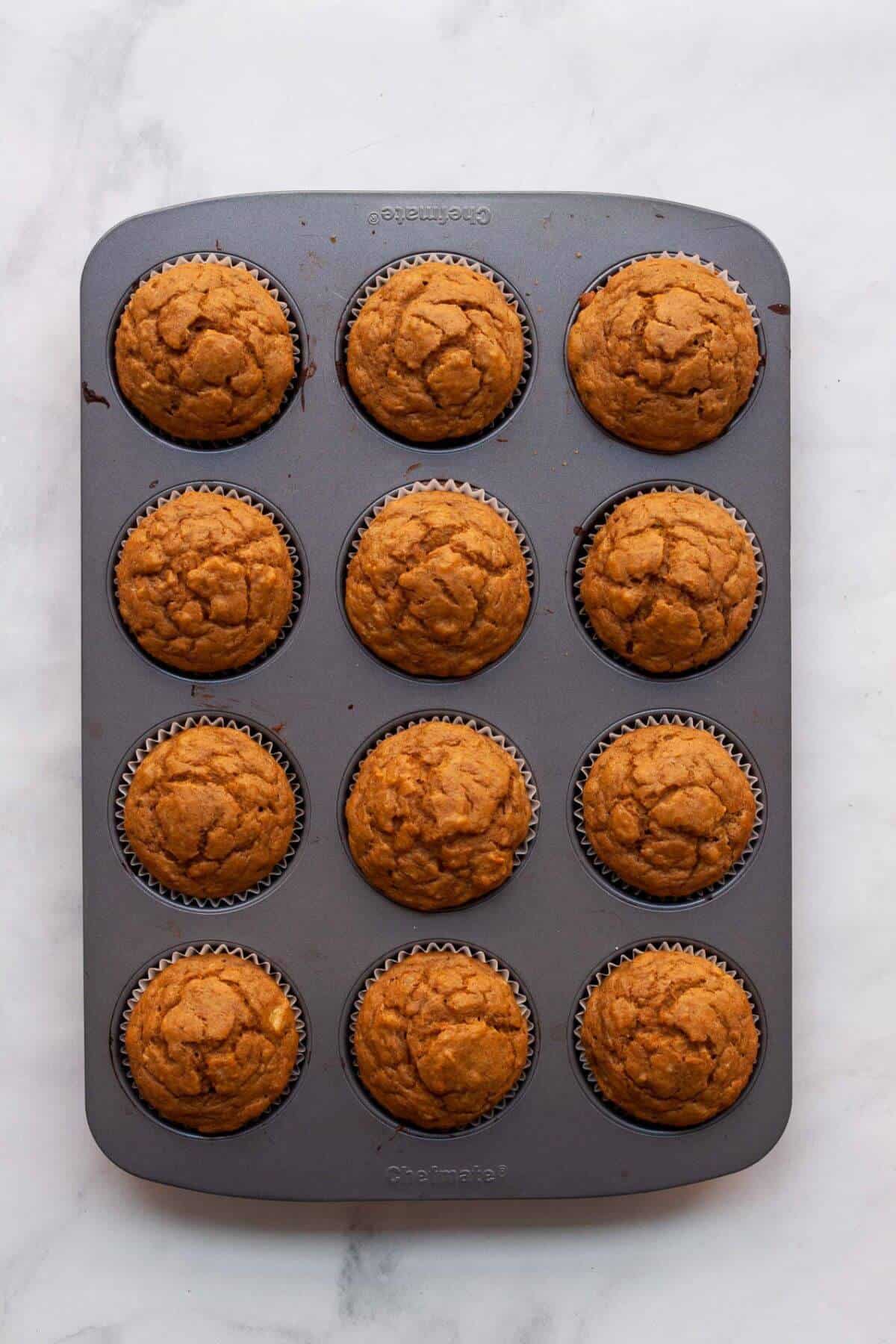 Freshly baked banana pumpkin muffins in a cupcake tin, golden brown and fluffy.
