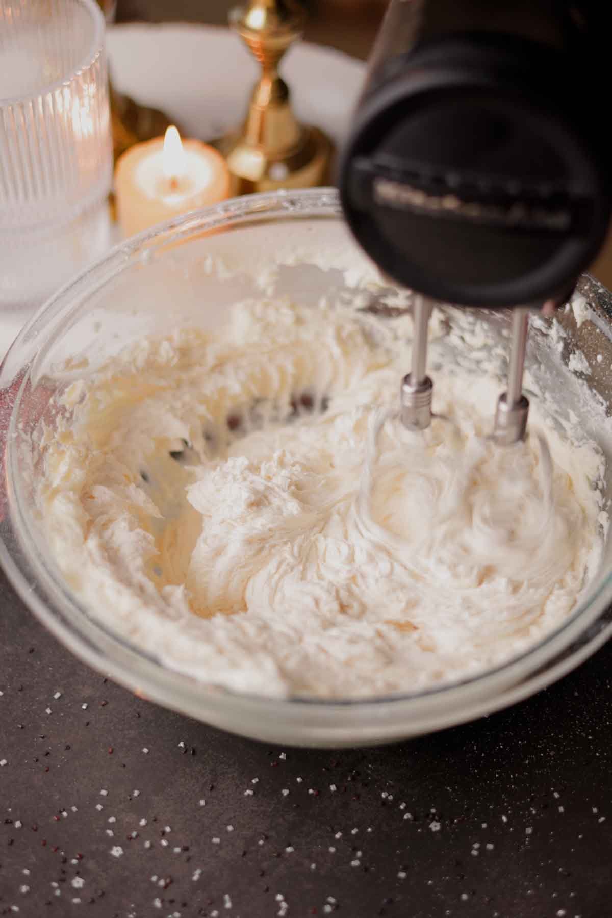beating butter and powdered sugar for frosting with an electric mixer