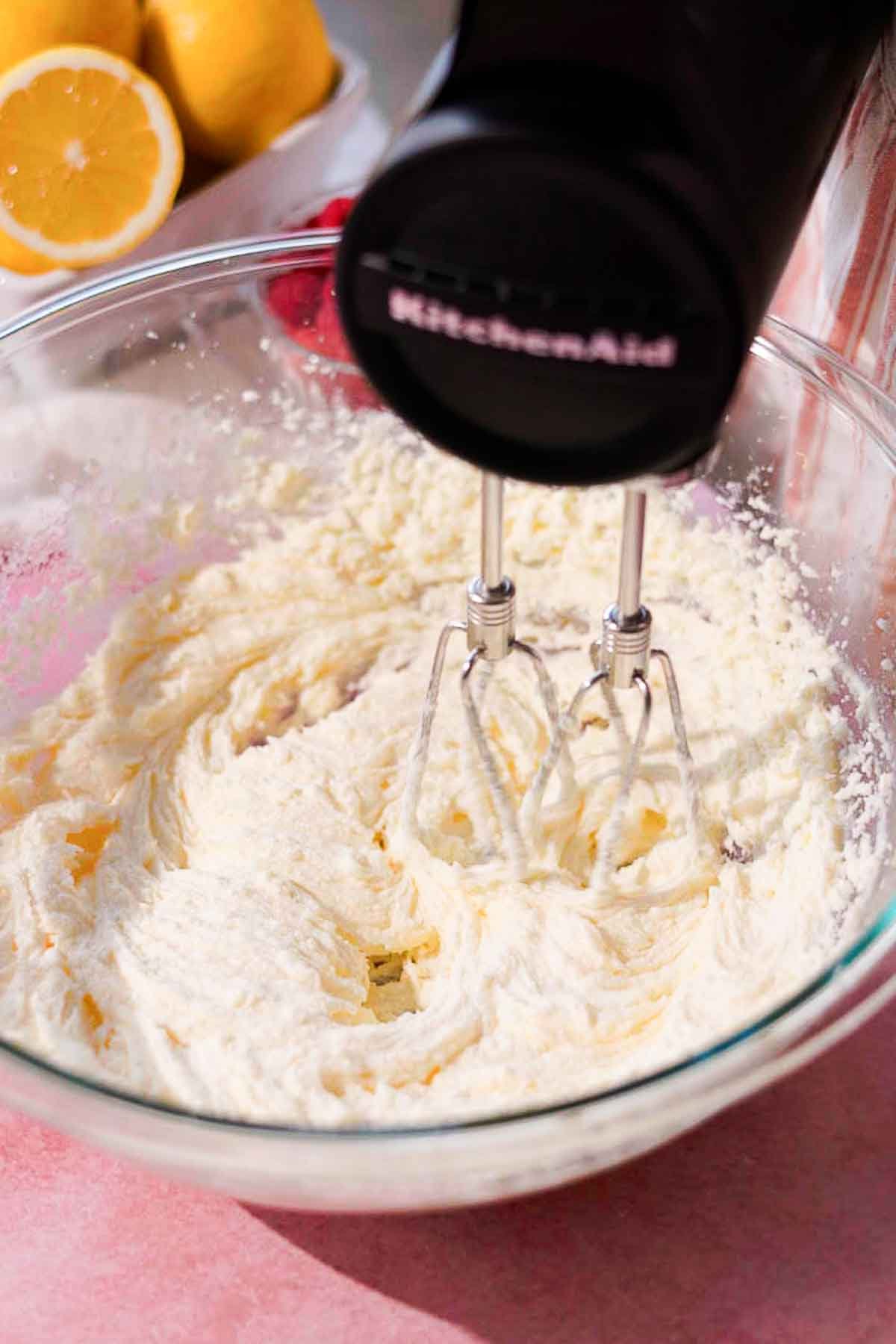 beating butter, sugar, and oil in large glass bowl with electric hand held mixer 
