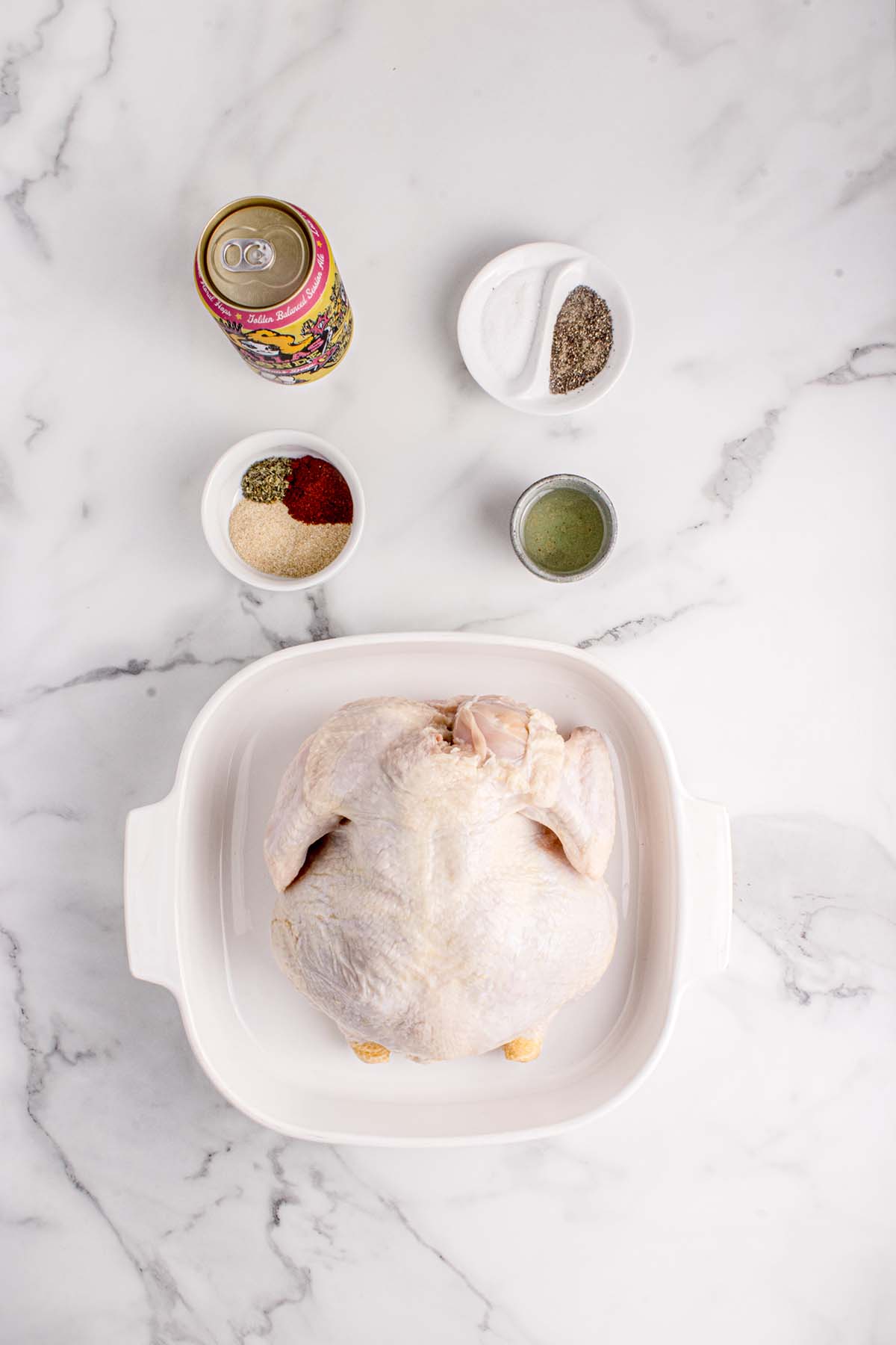 A raw chicken, spices, a beer can, and olive oil. 