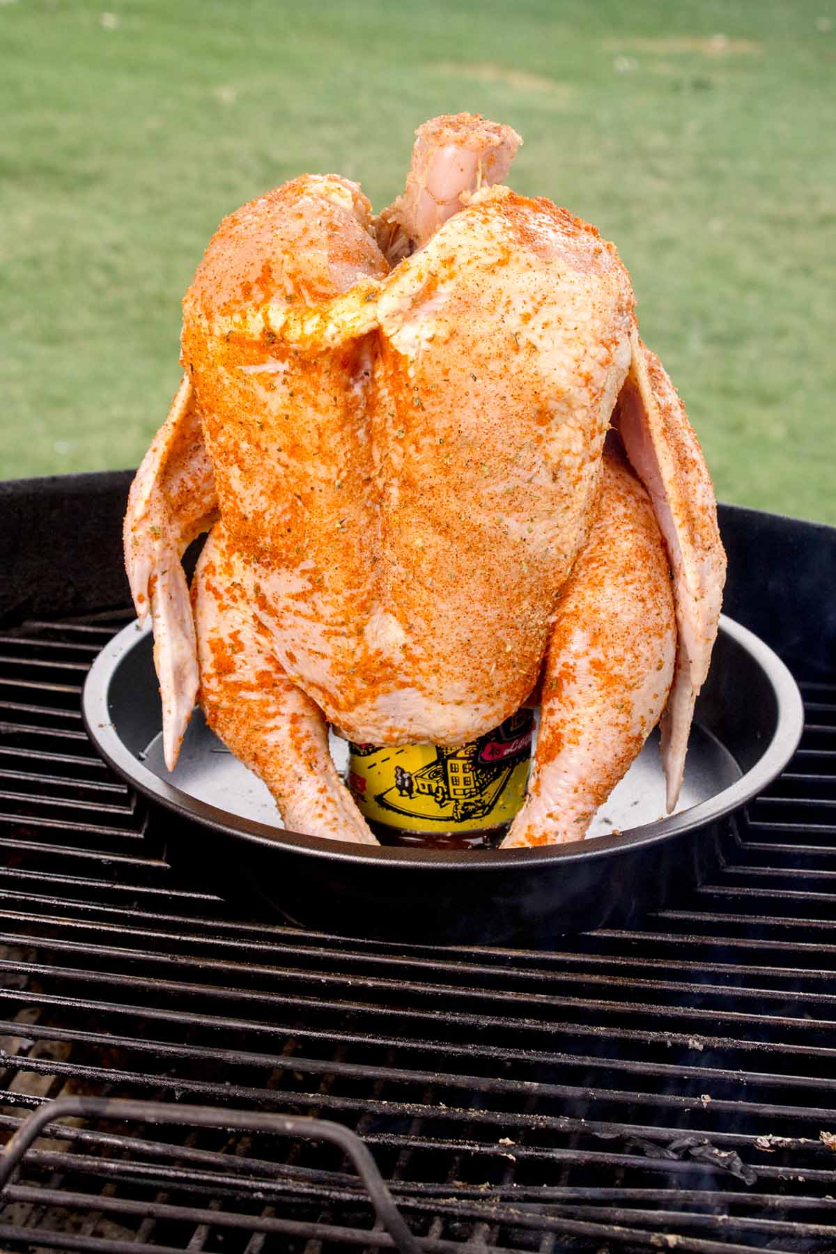 A whole chicken cooking on the grill. 