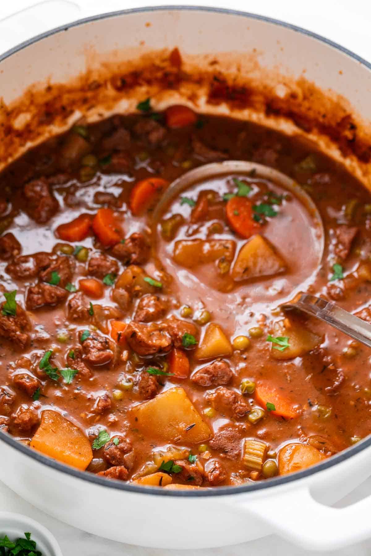 Vegan beef stew in a pot with a ladle.