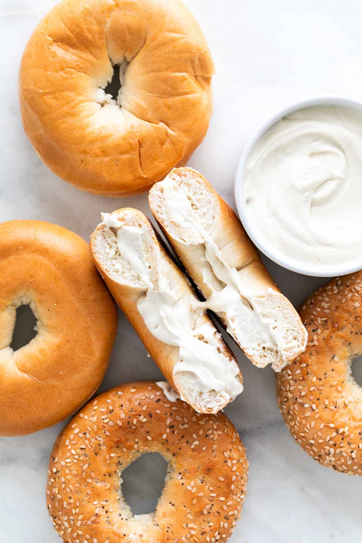 Bagels with vegan cream cheese spread, plus a bowl of extra vegan cream cheese.