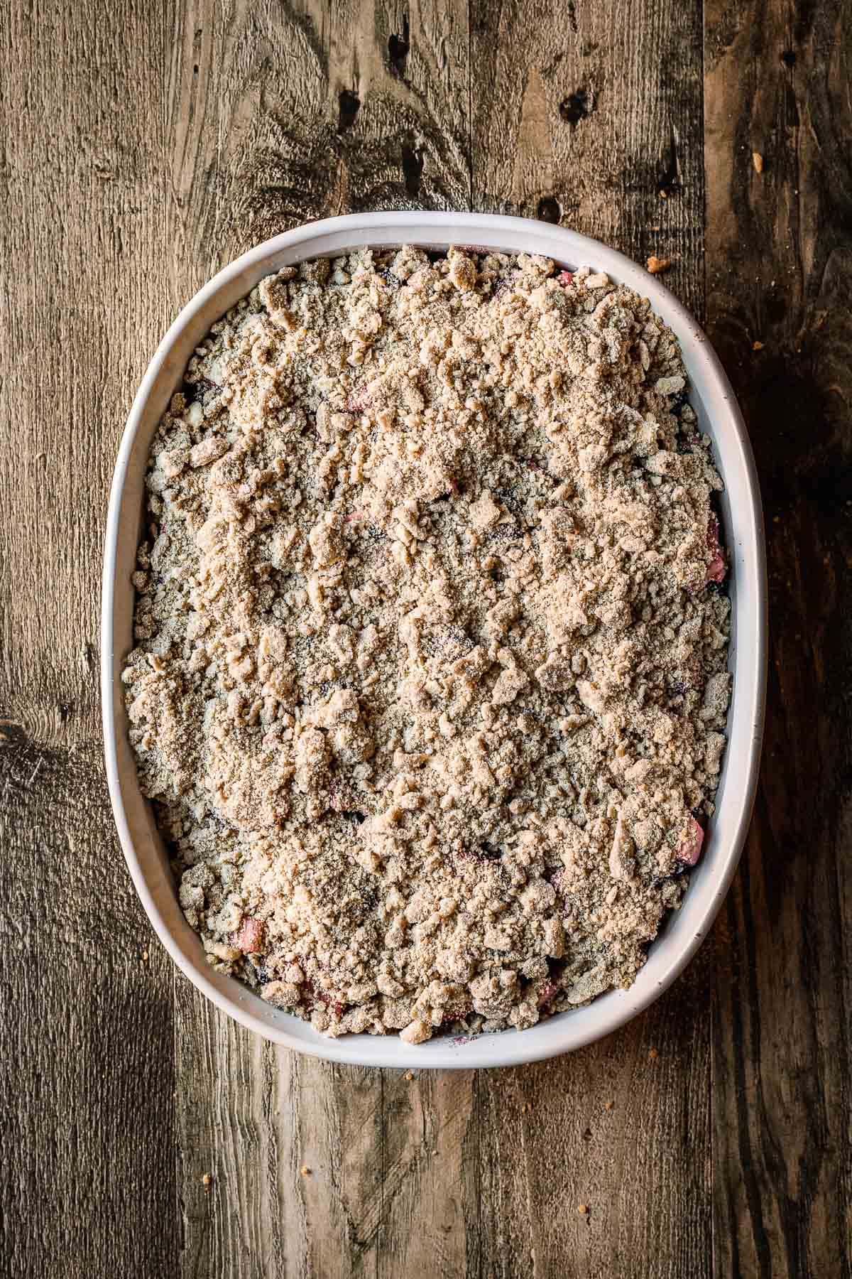 A baking dish filled with fruit and covered with crumble topping.