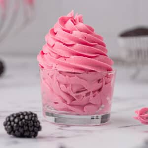 Blackberry buttercream frosting in a glass.