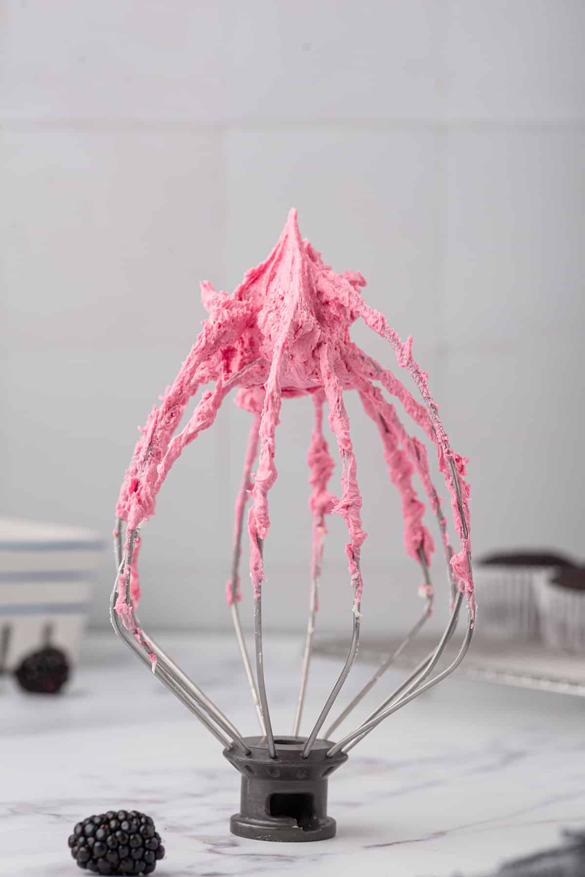 A whisk attachment with frosting on it.