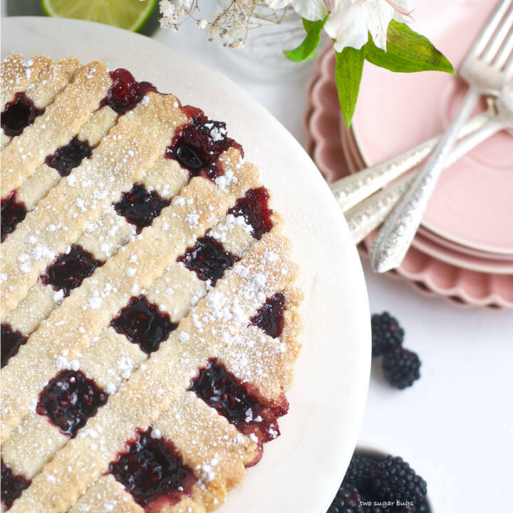 blackberry crostata on a serving plate with plates and forks