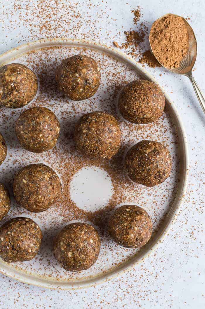a plateful of vegan chocolate chip peanut butter energy bites dusted with cacao with one missing.
