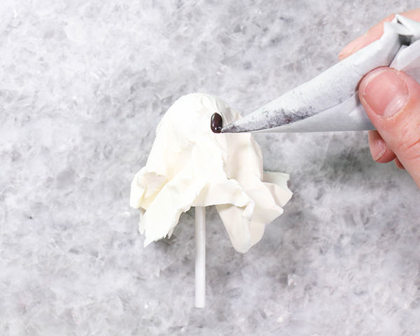 Chocolate Lollipop Ghosts - how to make edible lollipop ghosts for Halloween cakes and cupcakes using white chocolate and suckers | by Erin Gardner for TheCakeBlog.com