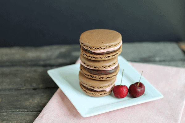a stack of chocolate macarons filled with cherry buttercream frosting and chocolate ganache