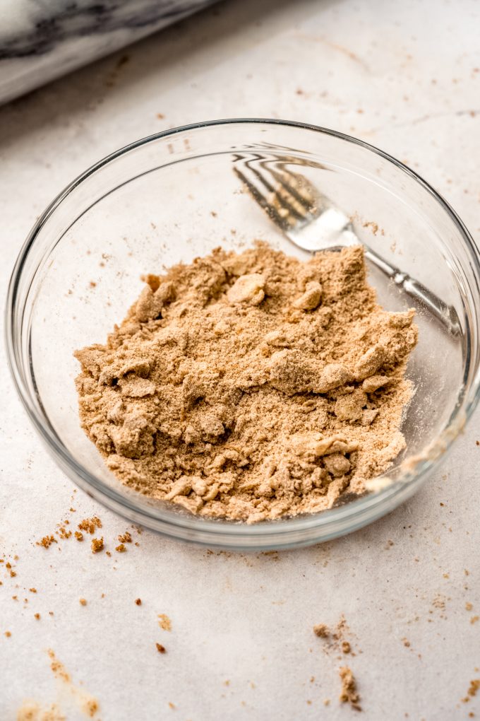 A bowl of streusel with a fork in the background.
