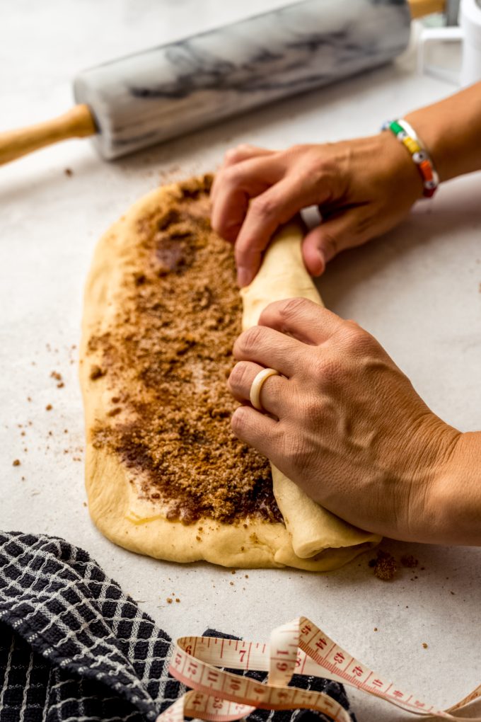 Someone's hands rolling up a rectangle of dough to make cinnamon babka.