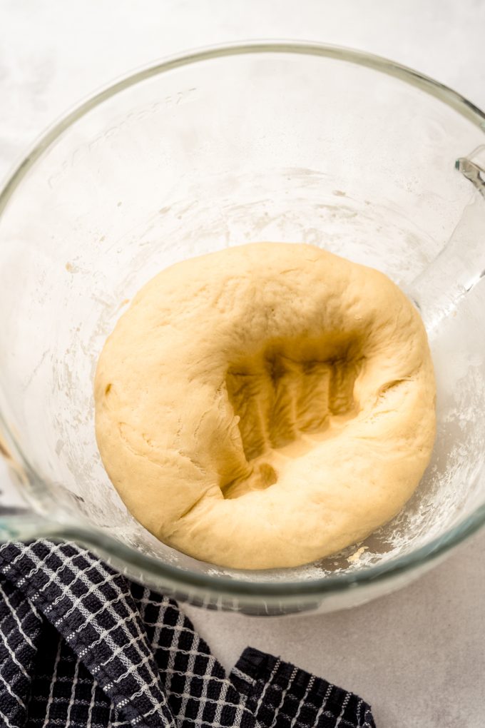 A fist print in a ball of dough that has risen in a bowl.