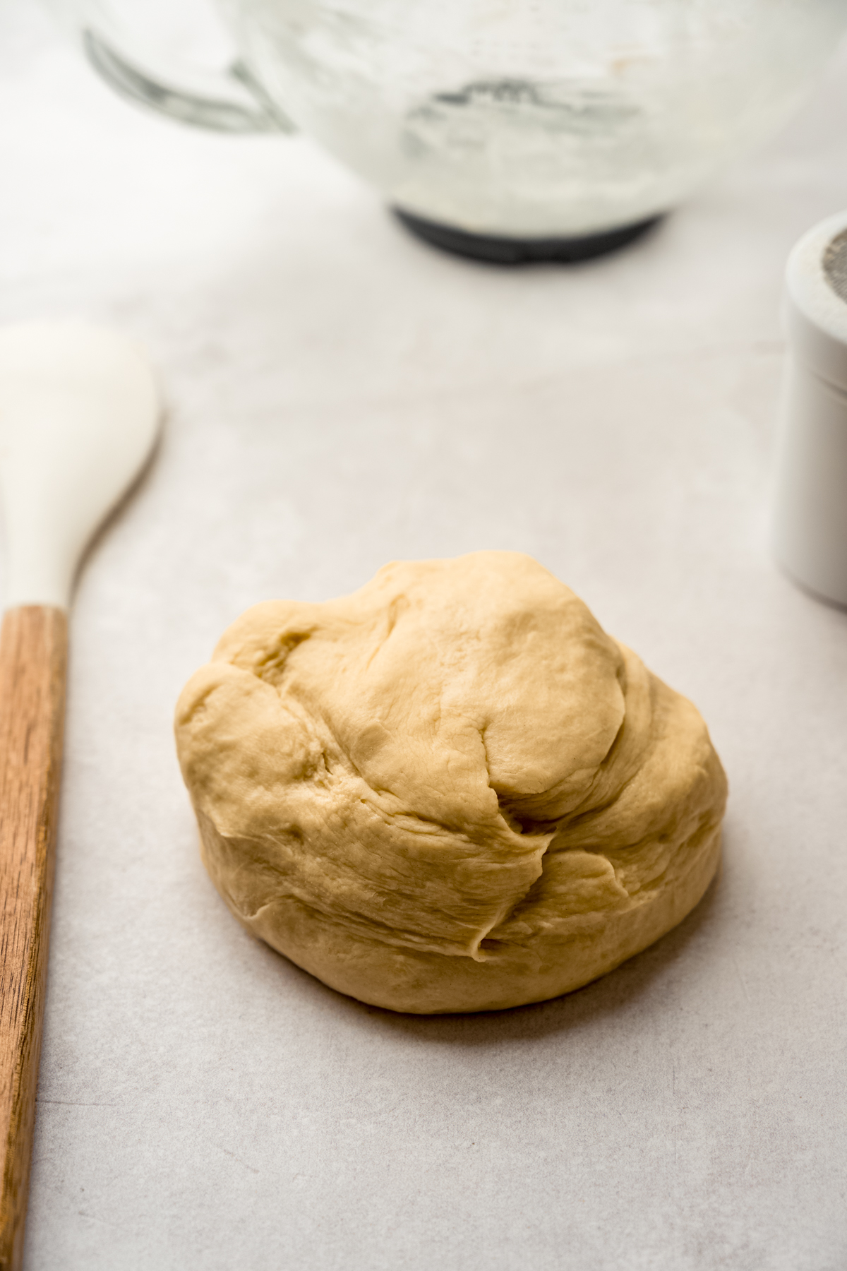 A ball of yeasted dough on a surface before rising.