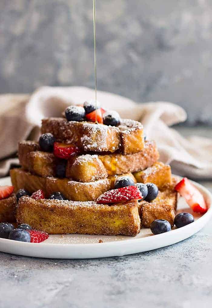 drizzling a stack of french toast sticks with syrup