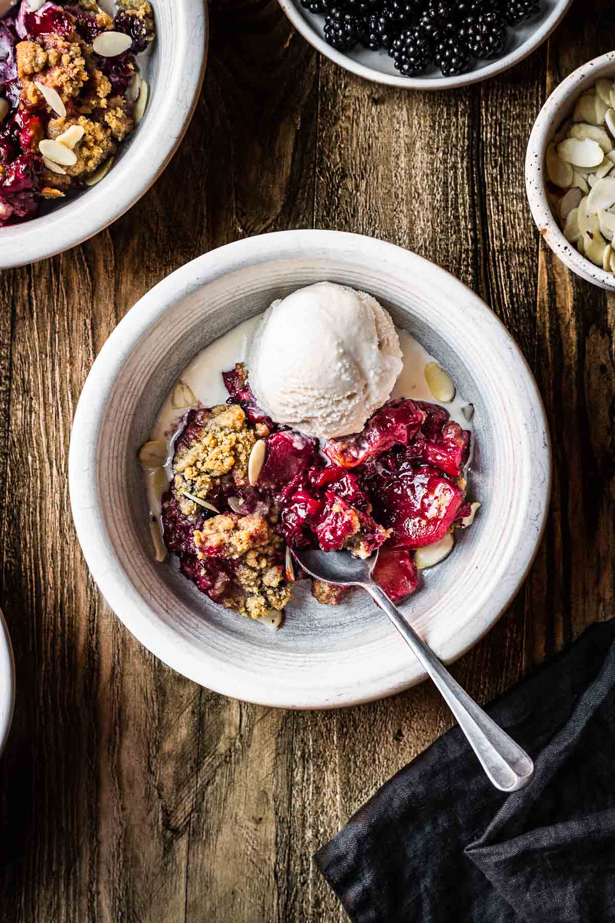 A serving of apple blackberry in a white bowl with a scoop of ice cream.