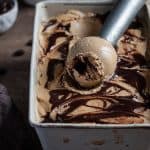 Vegan coffee ice cream in a metal tin with an ice cream scoop.