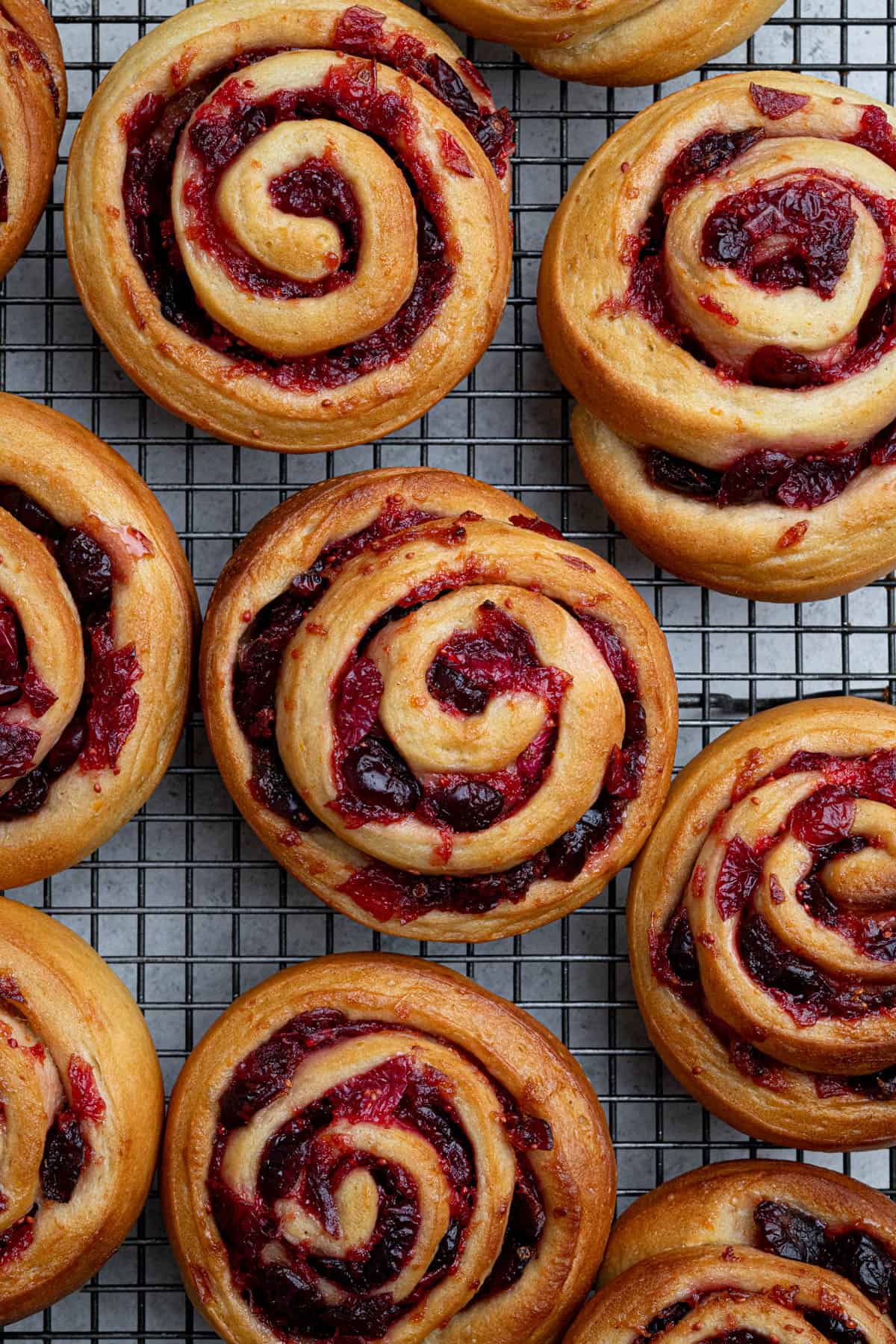 The baked vegan cranberry orange rolls on a wire cooling rack.