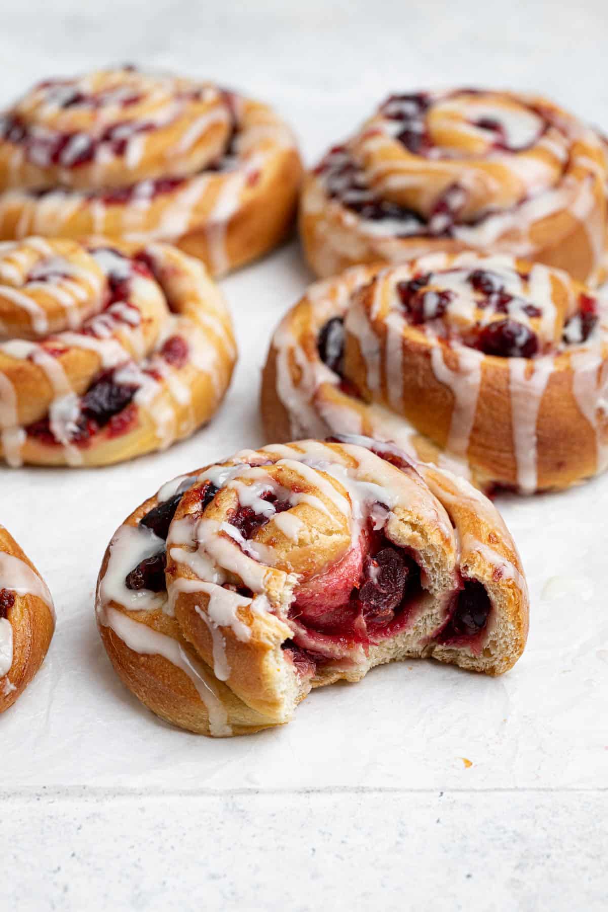 Close up of a vegan cranberry orange roll with a bite taken out of it.