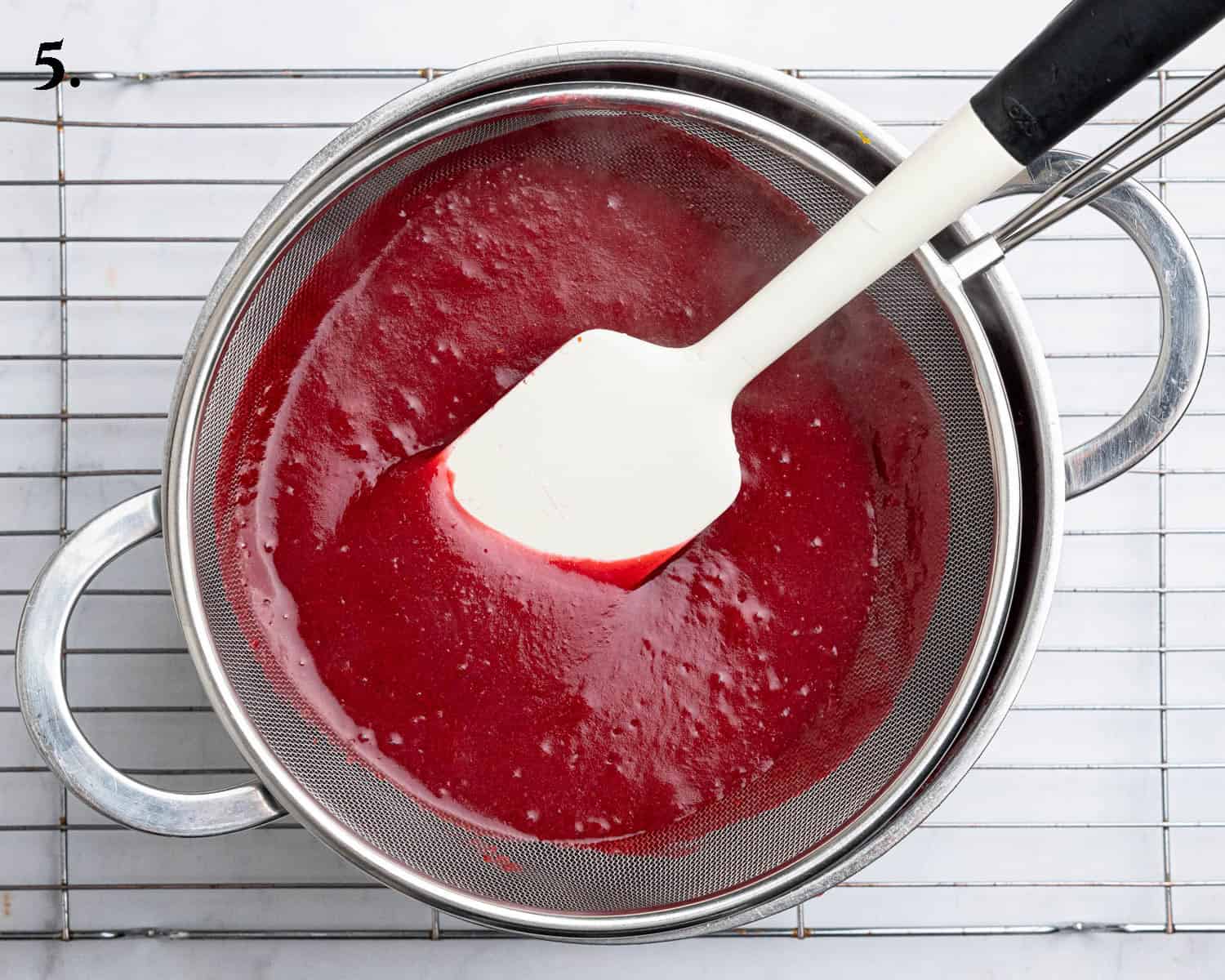 Step 5, scraping the blended cranberry mixture through a sieve.