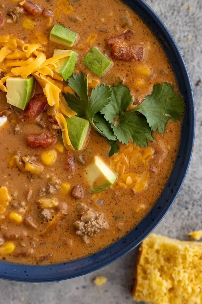 Close up of creamy taco soup with all the toppings. Cornbread off to the side. 