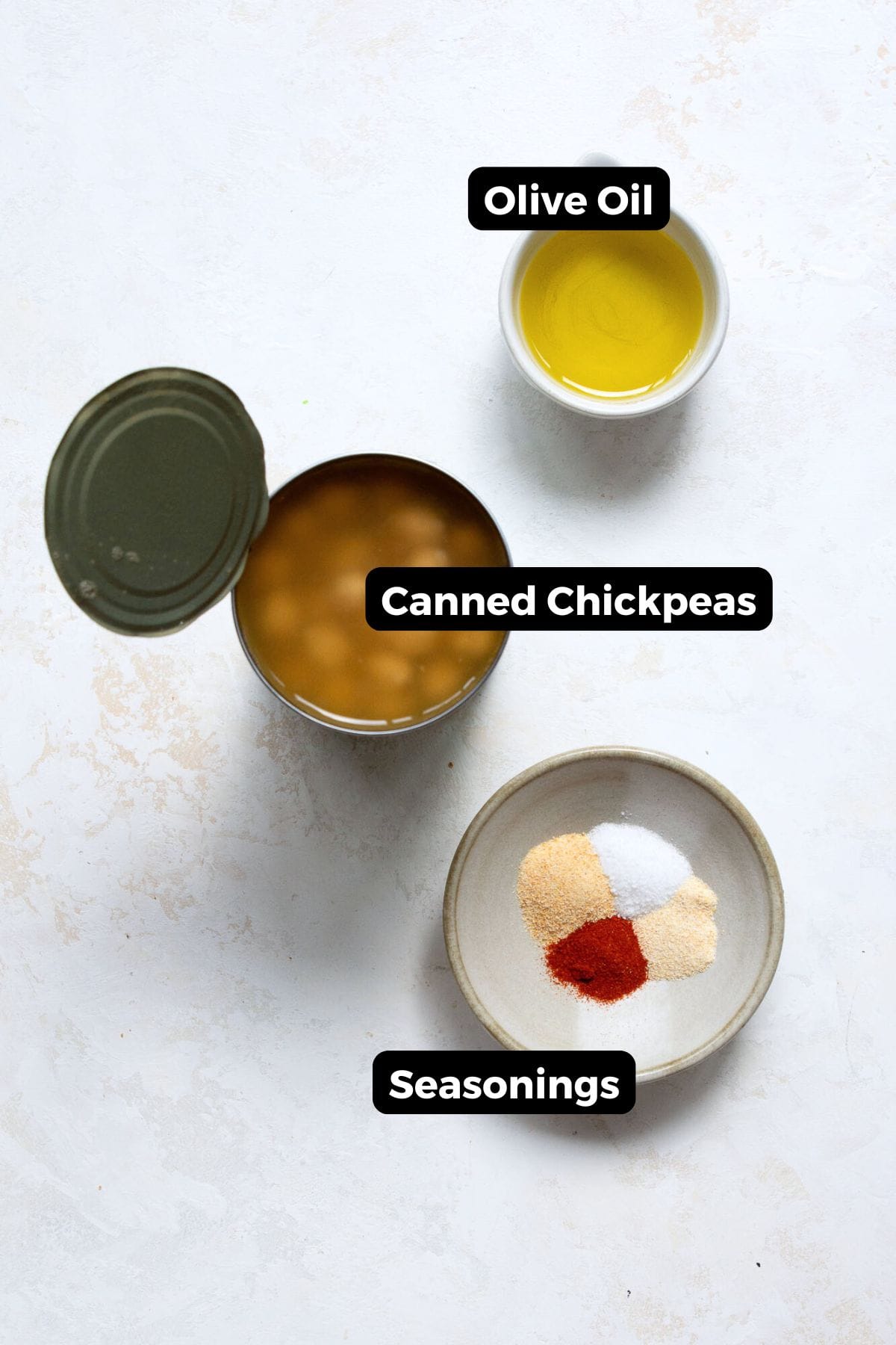 All labeled ingredients for crispy air fryer chickpeas laid out in bowls: canned chickpeas, olive oil, salt, garlic powder, paprika, and onion powder.