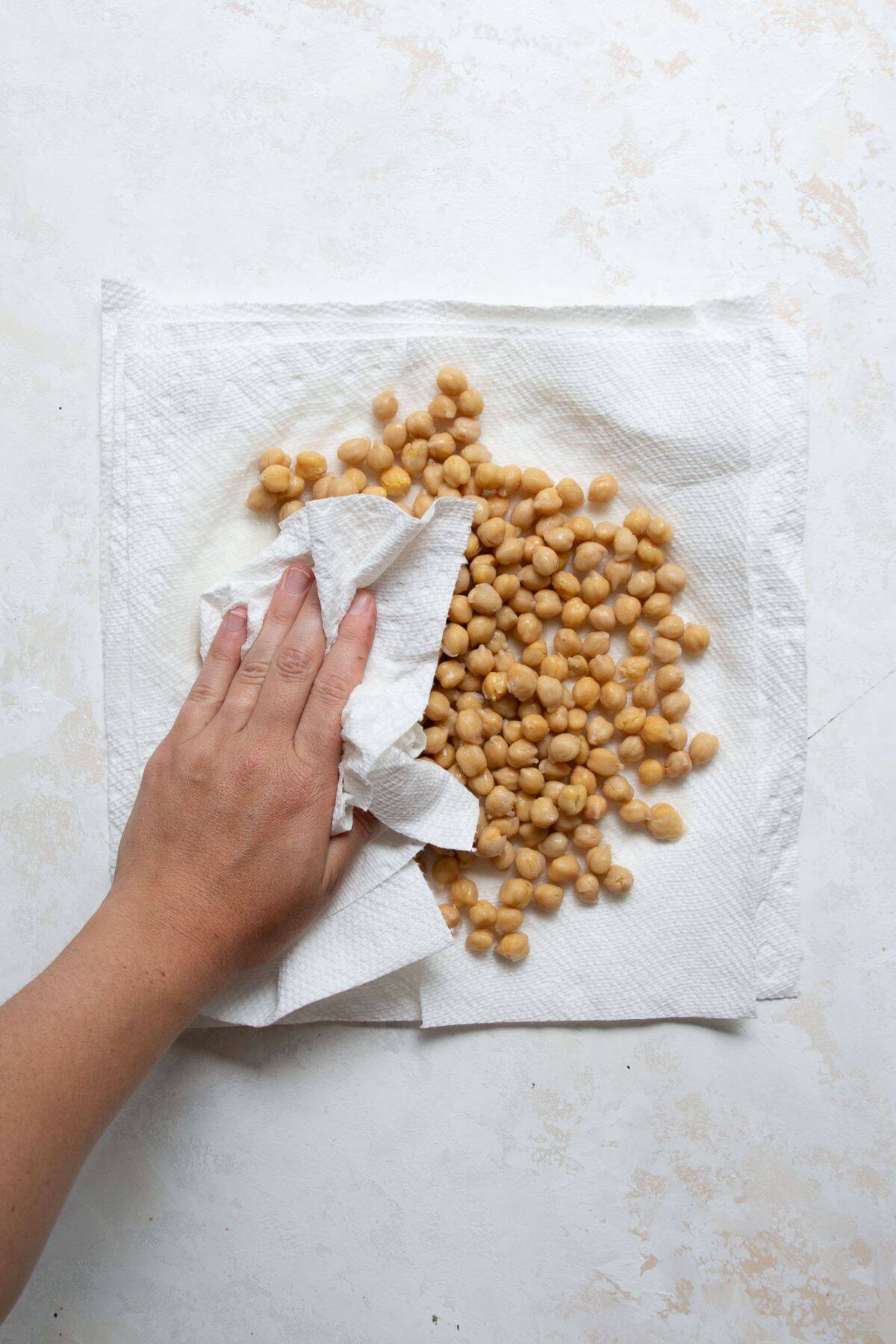 Patting canned chickpeas dry with a paper towel to remove moisture before air frying for extra crispiness