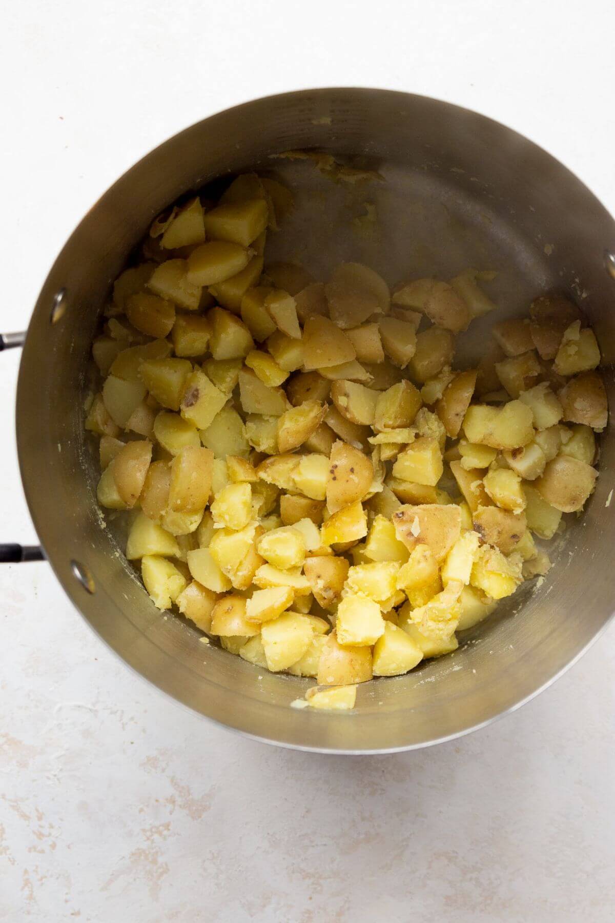 parboiled potatoes in a pot after shaking them to ruff up the edges and make them fluffy