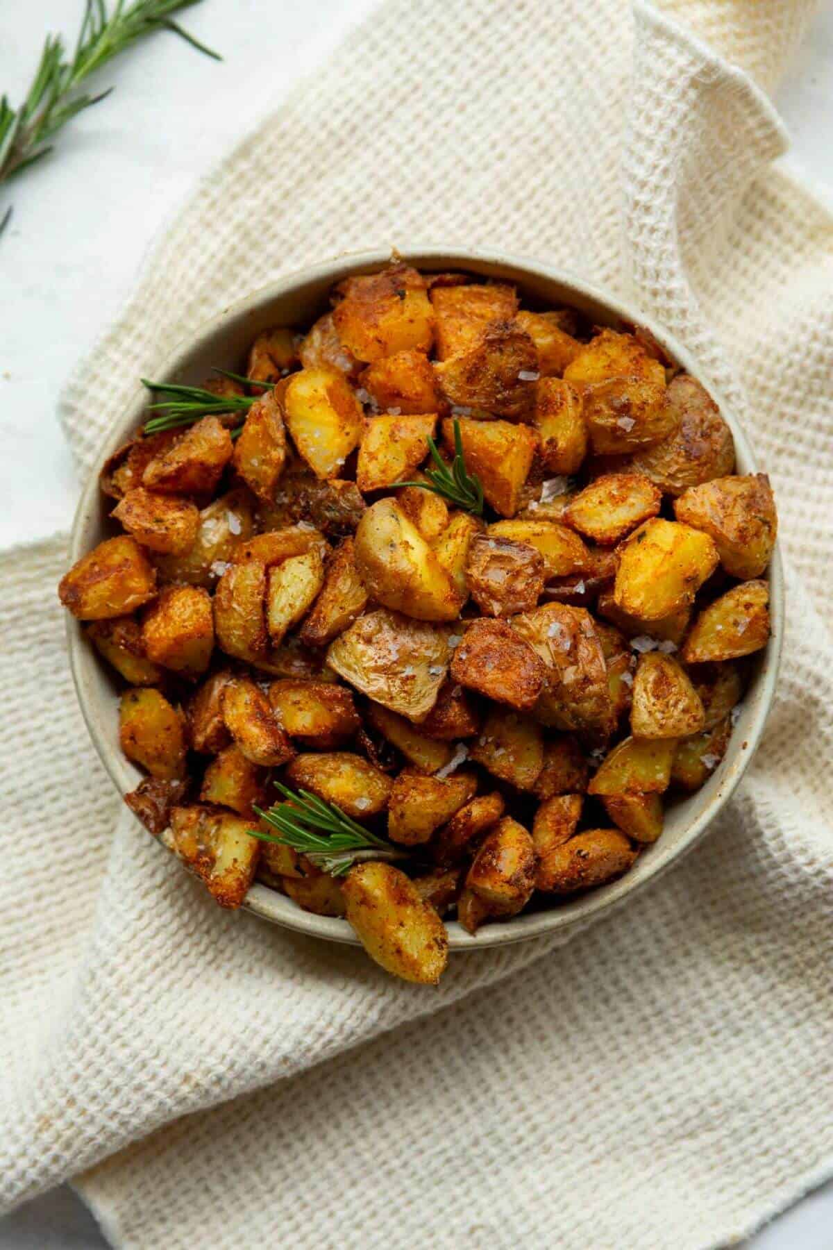 crispy and fluffy roasted potatoes in a bowl with rosemary