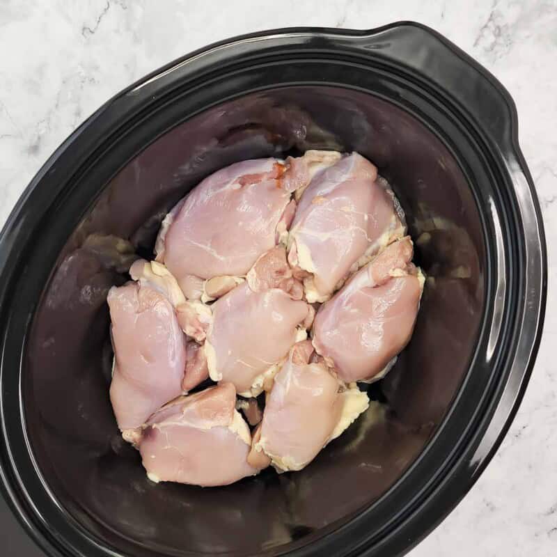 Overhead view of process shot 3 - lightly spray the inside of the crock pot with cooking spray and place the chicken in the crock pot.