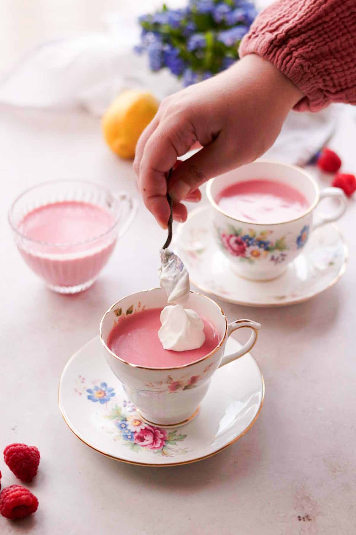 adding dollops of whipped cream onto raspberry posset