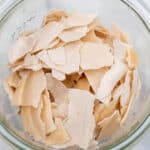 A glass jar with flakes of dried out sourdough starter.
