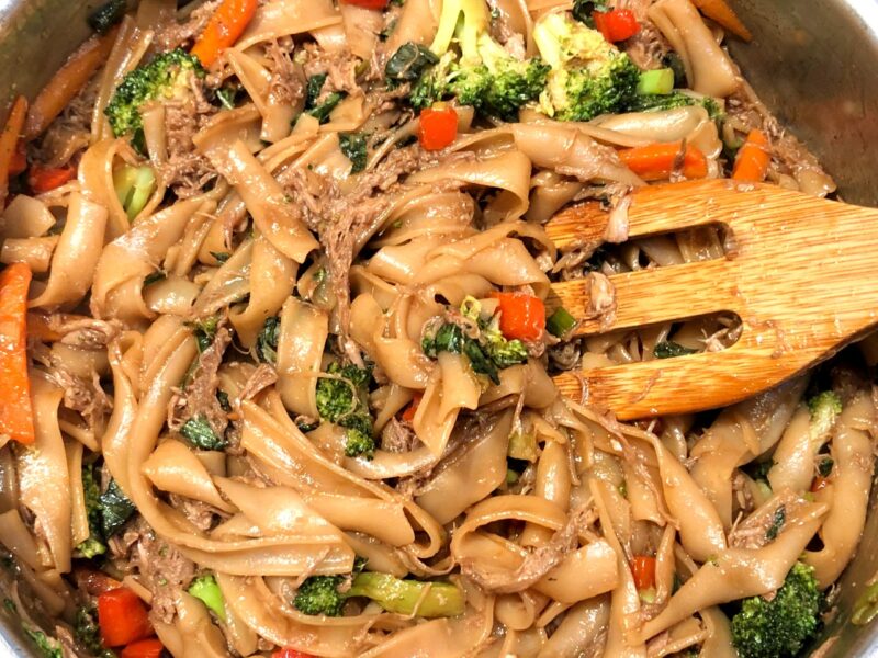pork drunken noodles in a pan with the sauce
