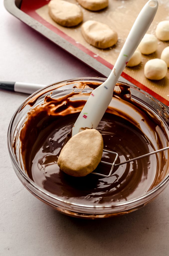 Someone is dipping a peanut butter egg into chocolate coating to make Easter candy.