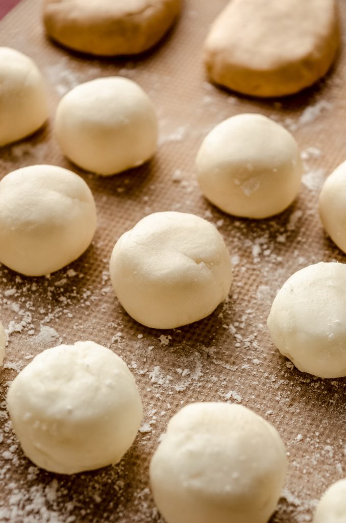Buttercream rounds filling on a baking sheet before getting dipped in chocolate.