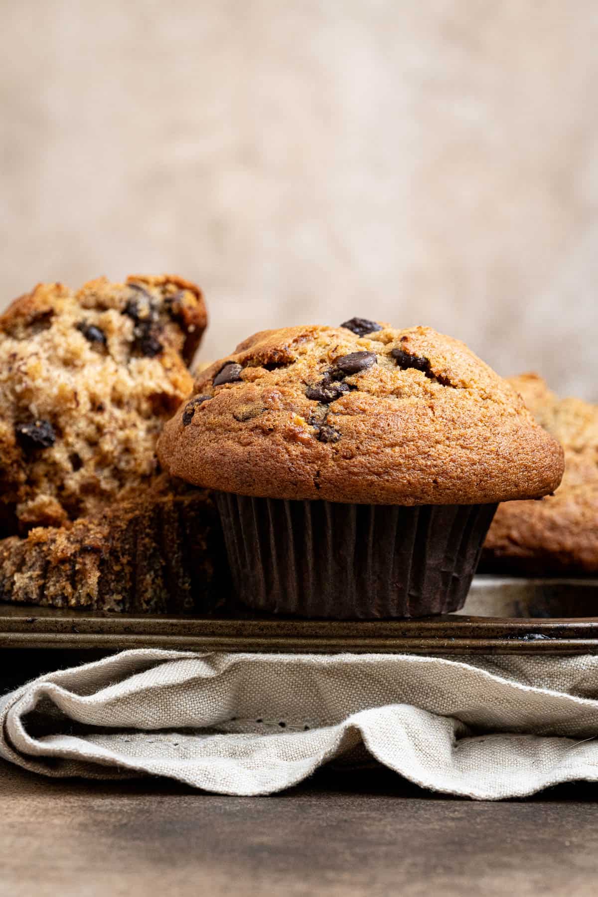Close up of a vegan banana muffin on top of a muffin pan.