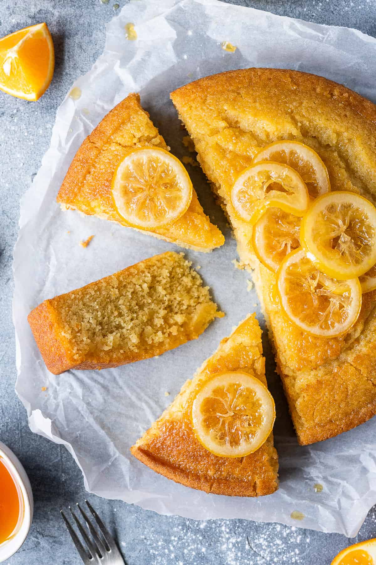 Slices of vegan semolina cake topped with candied lemon slices on a sheet of white baking parchment.