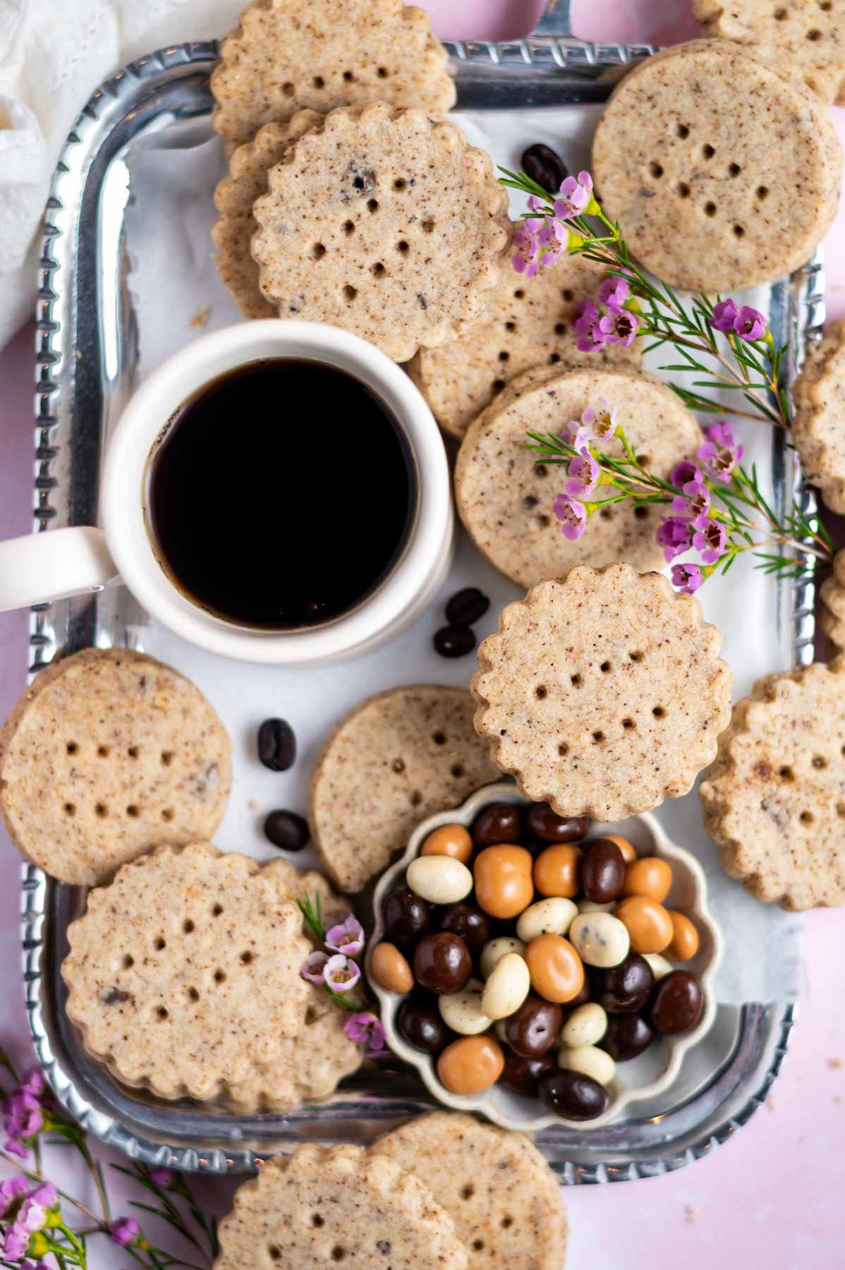 cookies on a tray with a cup of coffee and chocolate covered espresso beans