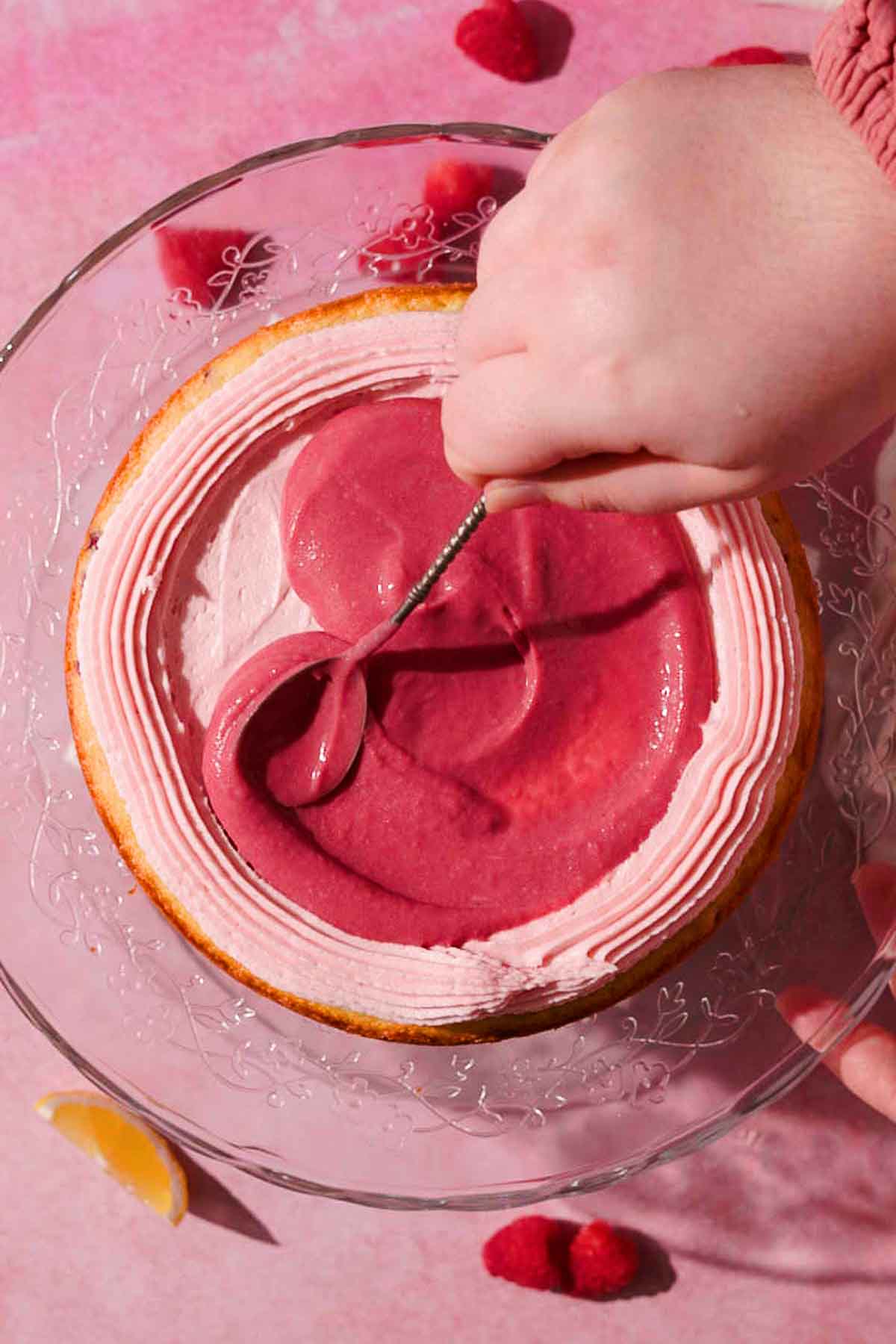 spreading raspberry curd into the middle of the cake with a piped border of frosting