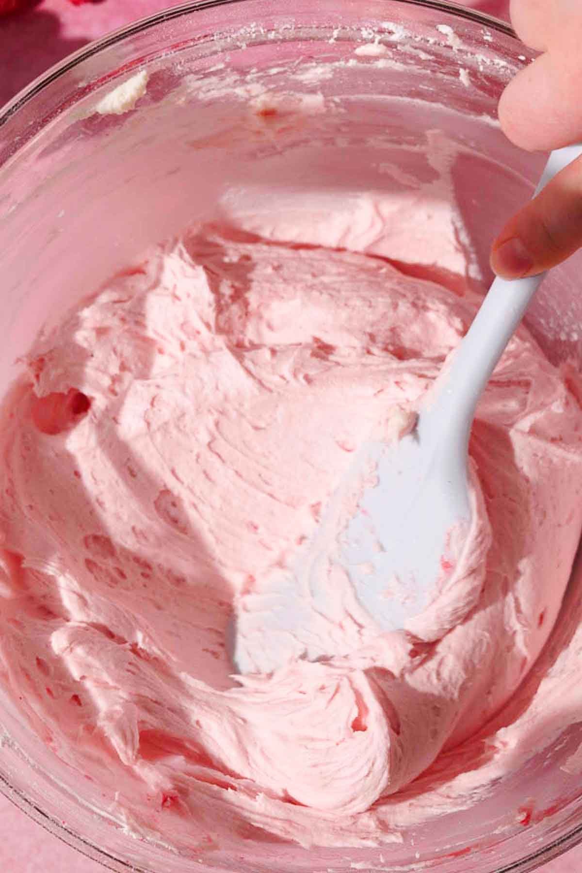 folding raspberry cream cheese frosting with silicone spatula