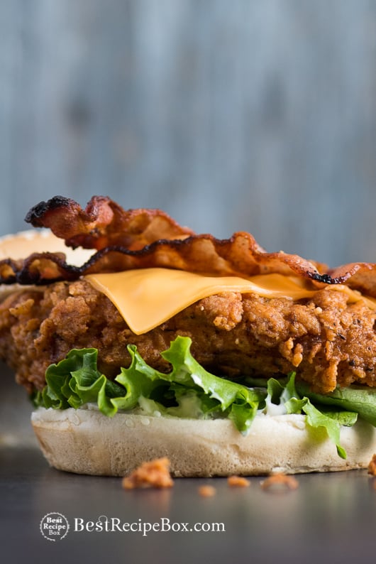 Fried Buttermilk Chicken Sandwich with Bacon & Cheddar on cutting board 