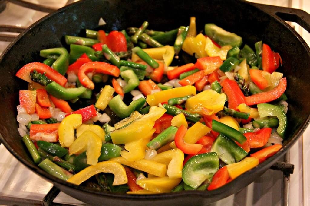 Sauteing vegetables in a large cast-iron skillet to make a frittata.