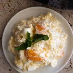 Overhead view of frog eye salad on a white plate garnished with fresh mint.