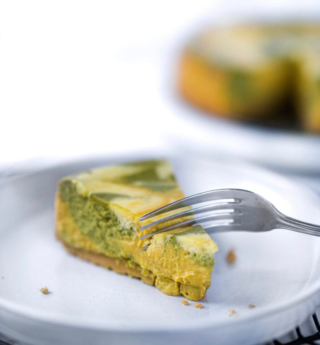 Fork cutting into piece of matcha pumpkin cheesecake