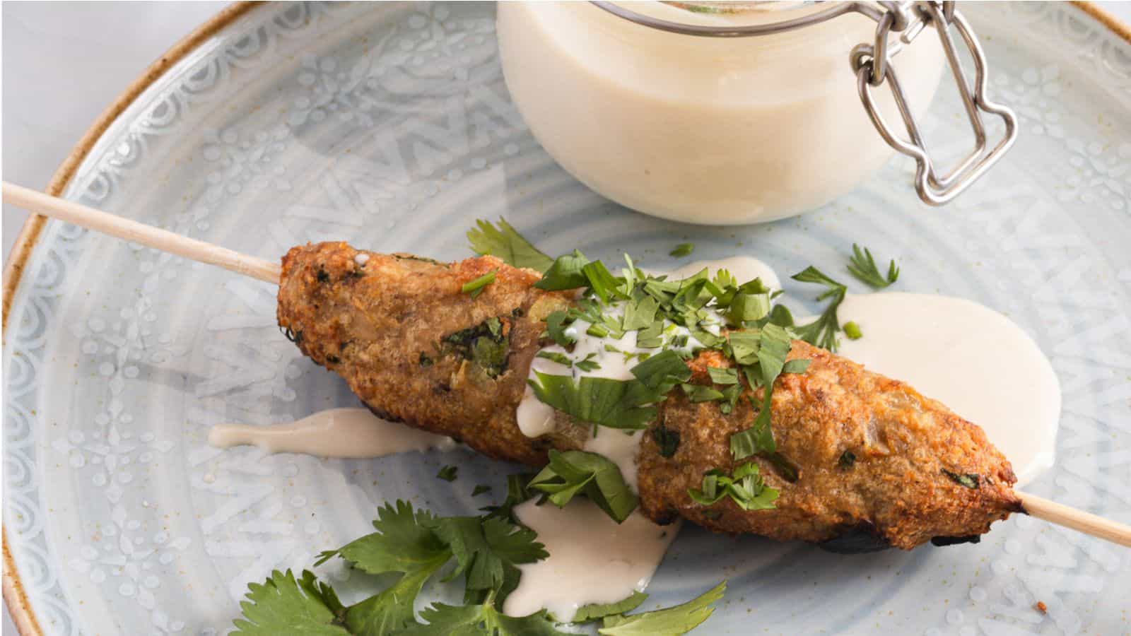 Chicken skewers on skewers with lemon wedges.