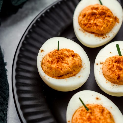 Halloween pumpkin deviled eggs on a black plate.