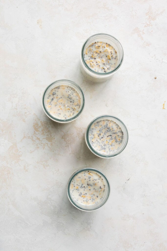 adding milk, yogurt, protein powder and chia seeds to rolled oats in mason jars