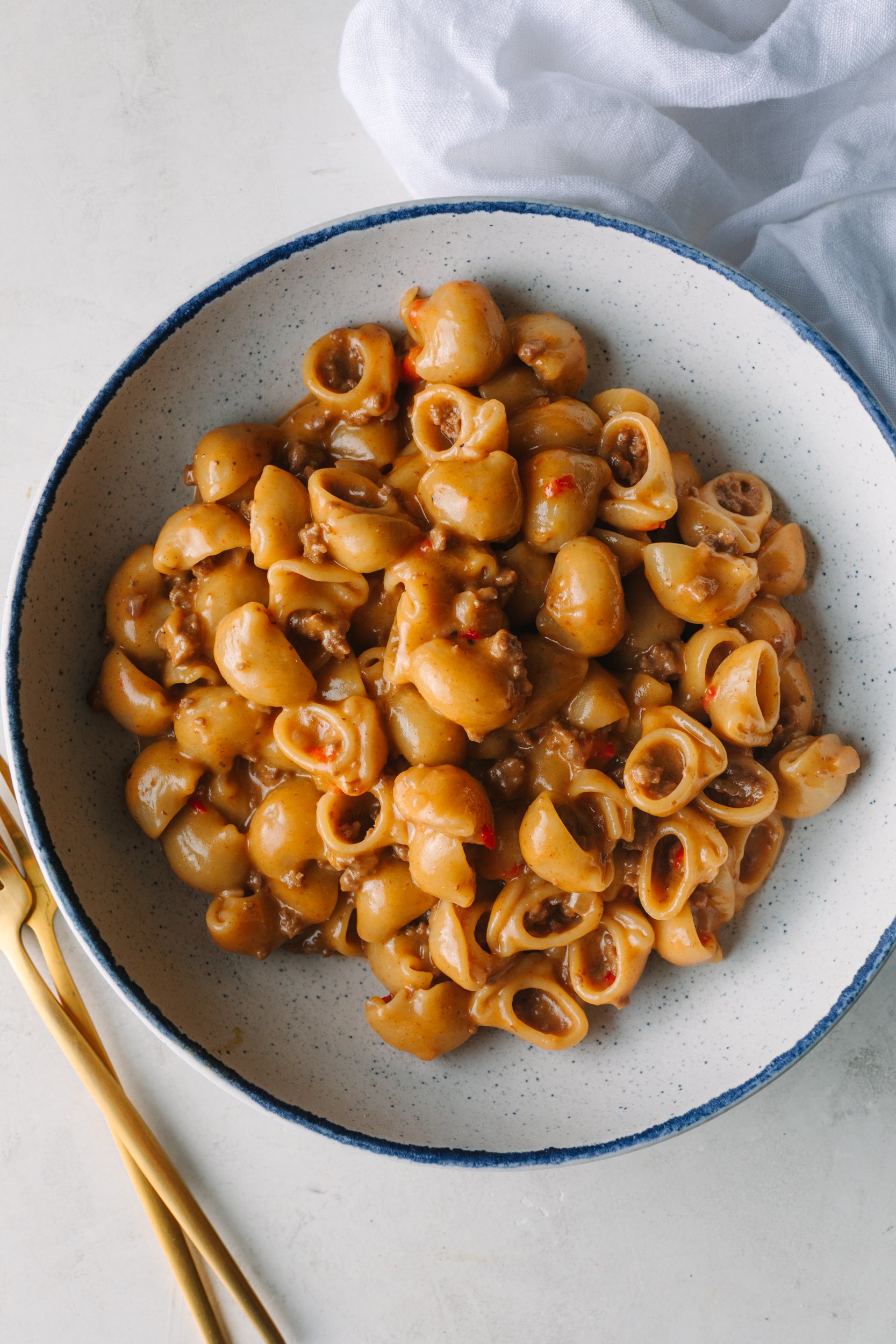 Bowl of Homemade Hamburger Helper with gold forks and a white napkin