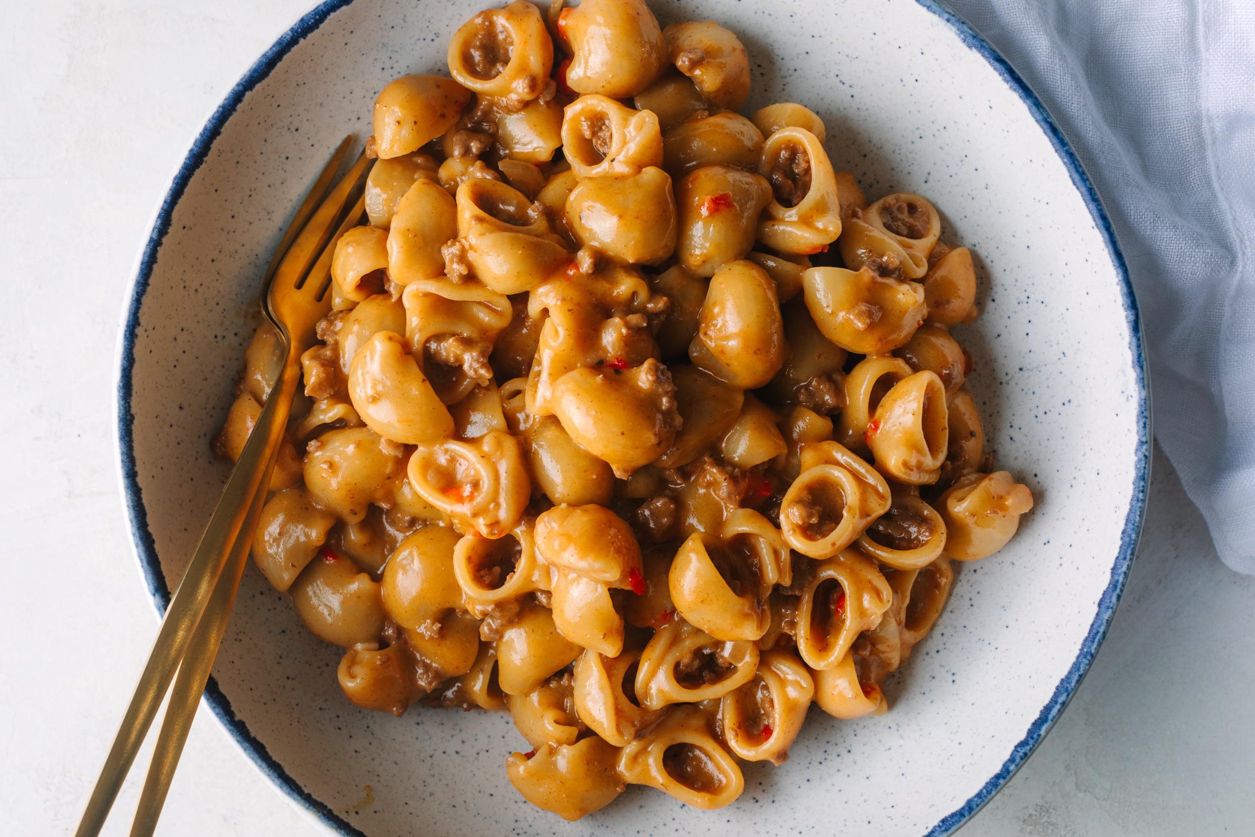 Bowl of Homemade Hamburger Helper with gold forks and a white napkin