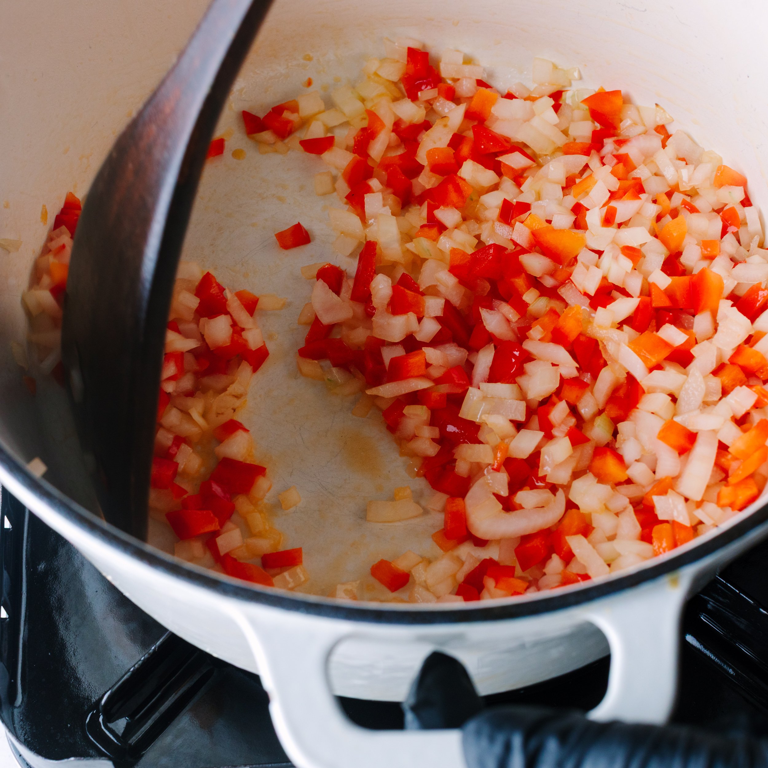 Sautéing diced onion, garlic, and peppers in a dutch oven 
